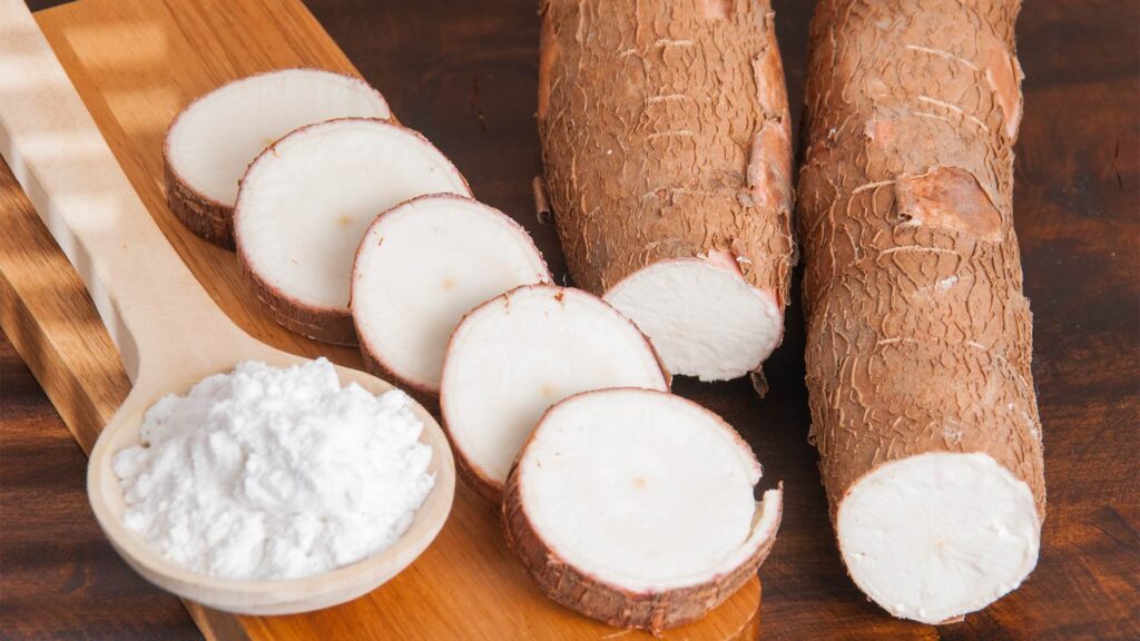 Brown Rice and Tapioca Starch. A close-up view showing sliced yuca roots beside a bowl of yuca flour on a wooden surface.