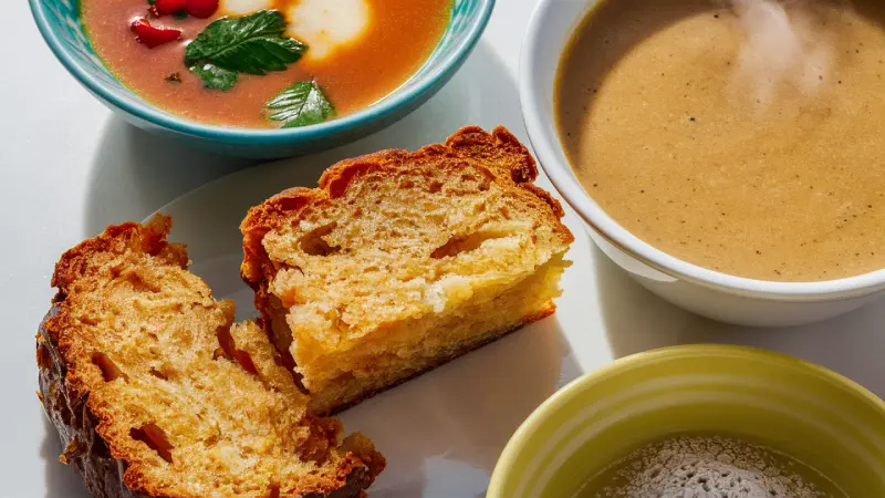 Tapioca Starch Benefits. A close-up view of a comforting meal setup featuring two types of soup—one creamy brown and the other tomato-based red-orange, both steaming hot—and a crispy, golden brown grilled cheese sandwich cut in half to reveal the melted cheese, all served on a pristine white surface