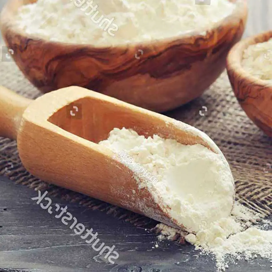 white flour on a rustic wooden surface, with a round wooden bowl filled with flour